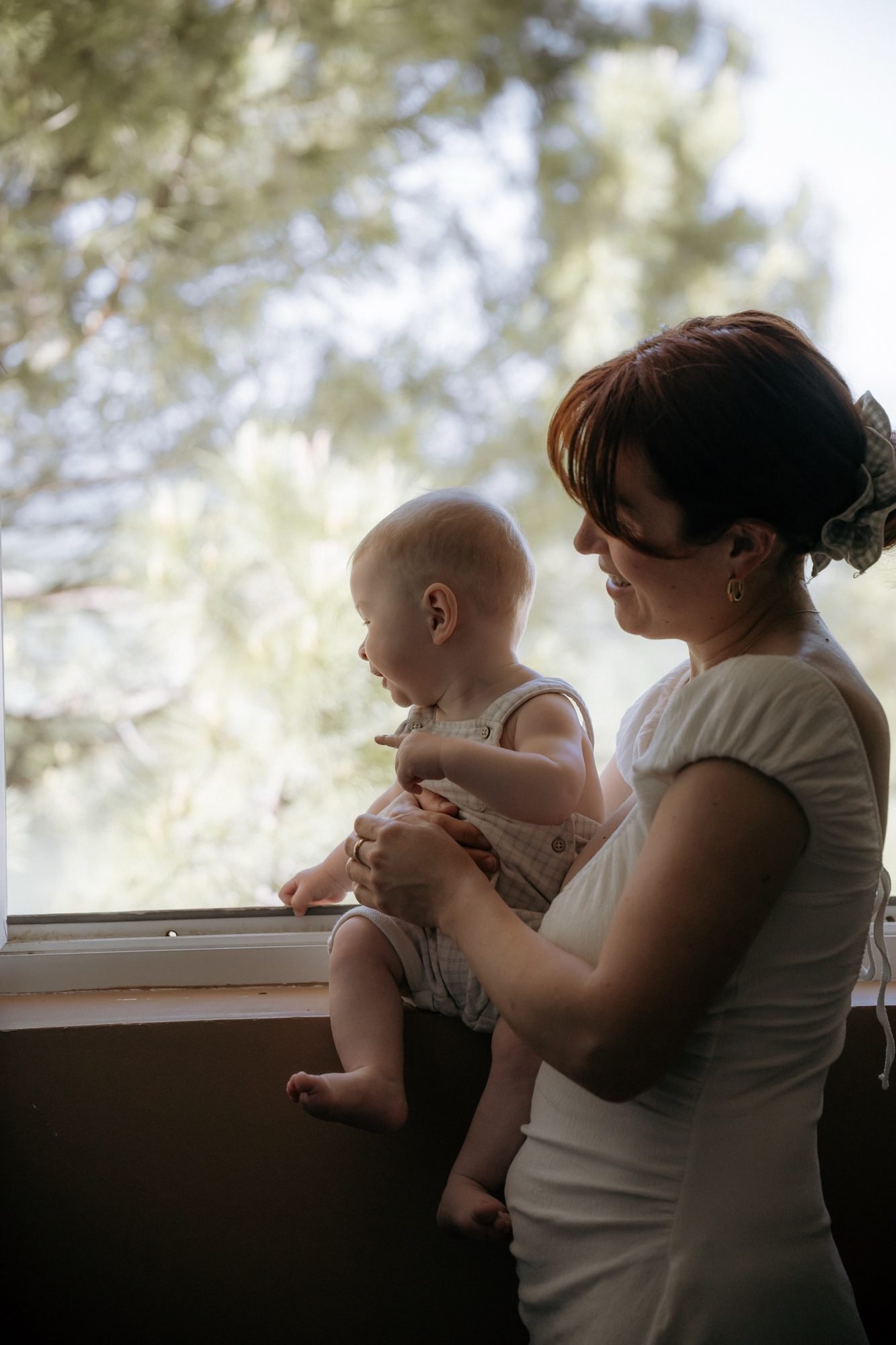 Bébé porté à bout de bras par sa maman, rires partagés