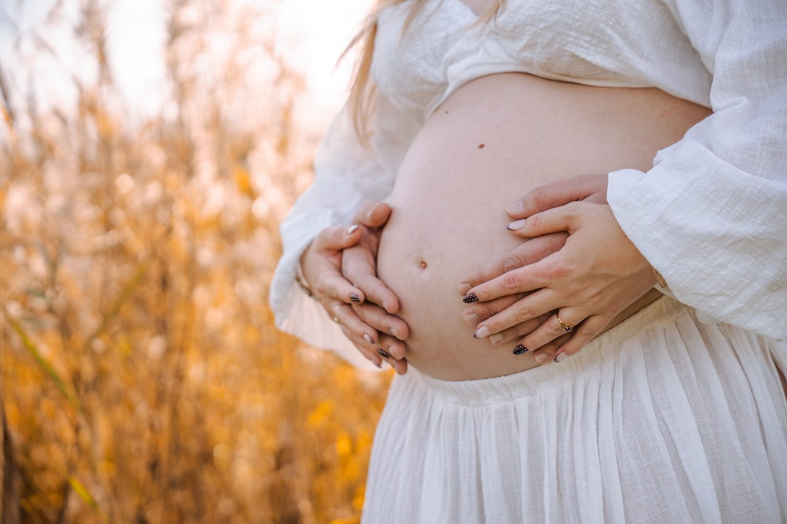 Femme enceinte souriante dans un parc, robe fluide