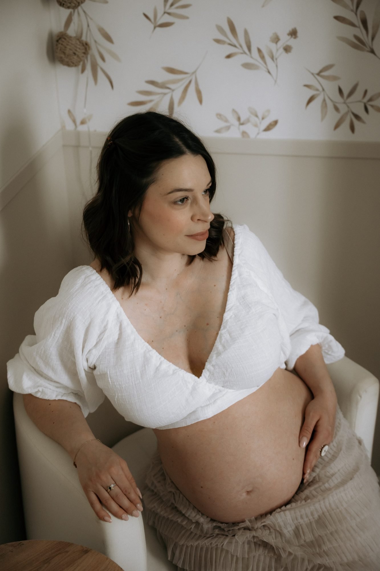 Femme enceinte assise près d'une fenêtre, bouquet de fleurs roses