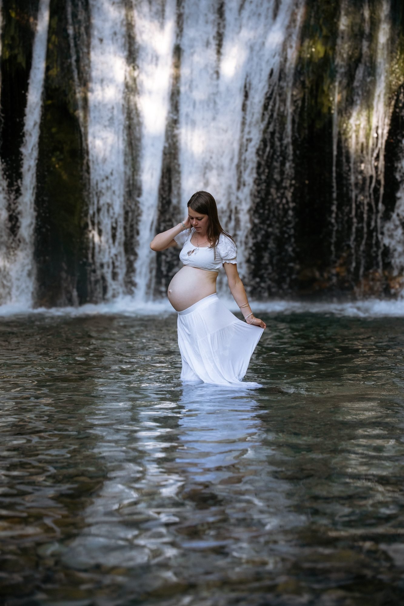 Femme enceinte de profil au bord de l'eau, lumière du soir