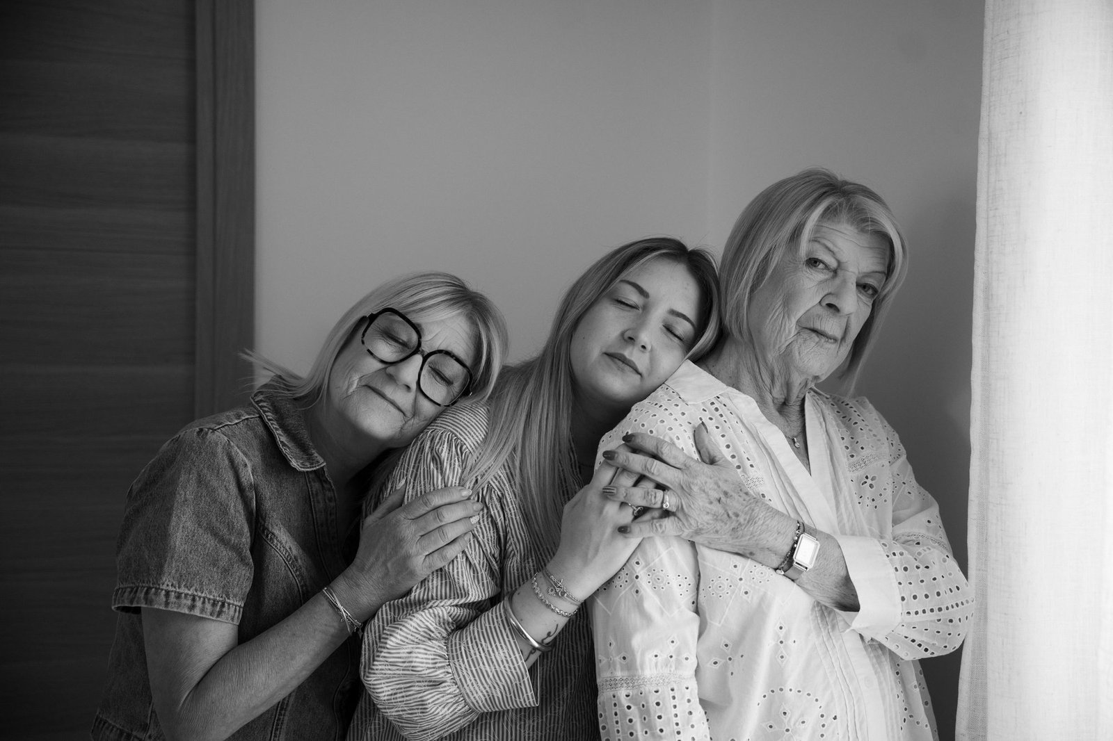 Trois générations de femmes réunies près d'une fenêtre, lumière douce