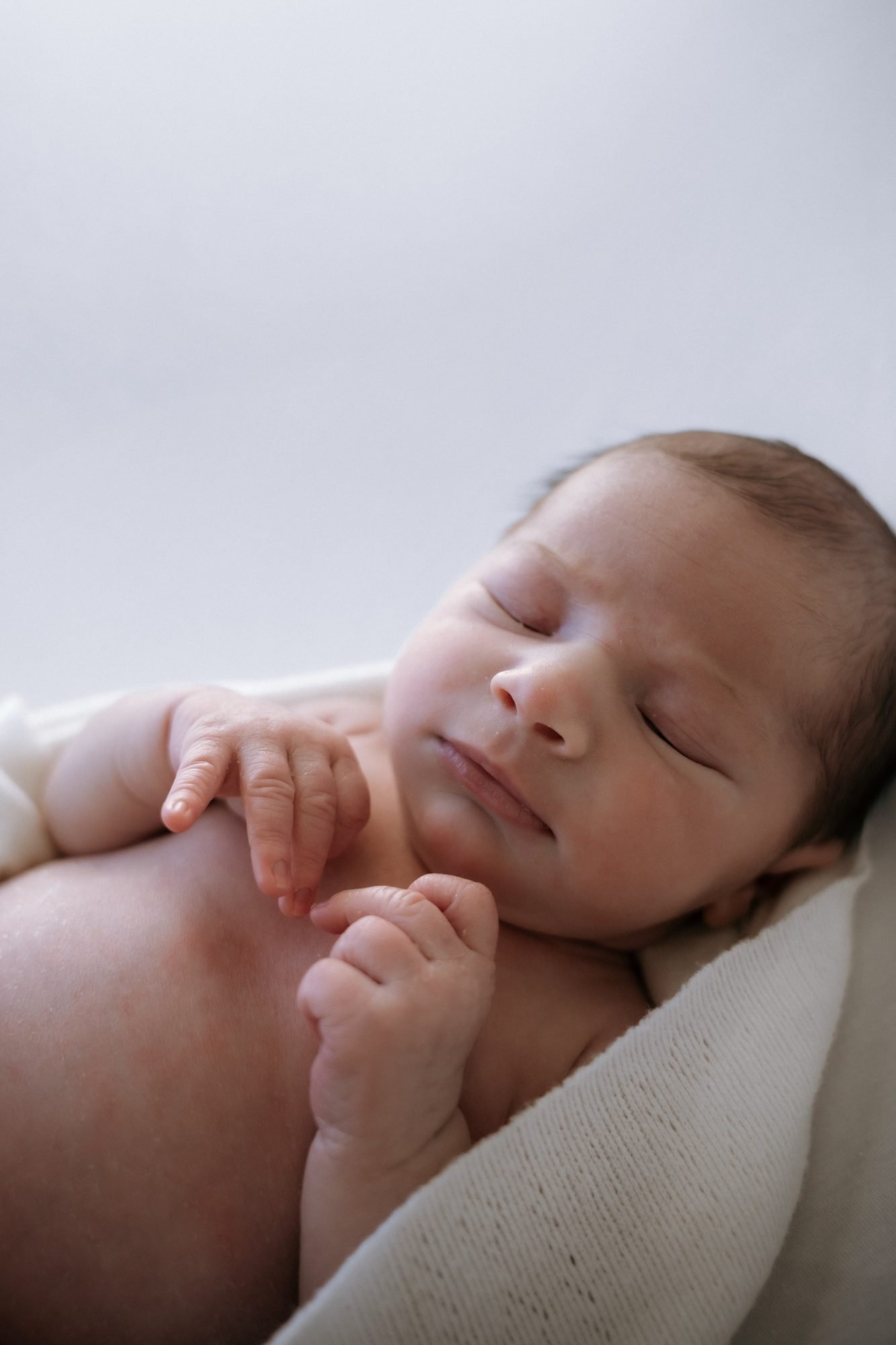 Gros plan sur le visage endormi d'un nouveau-né, main portée à la bouche