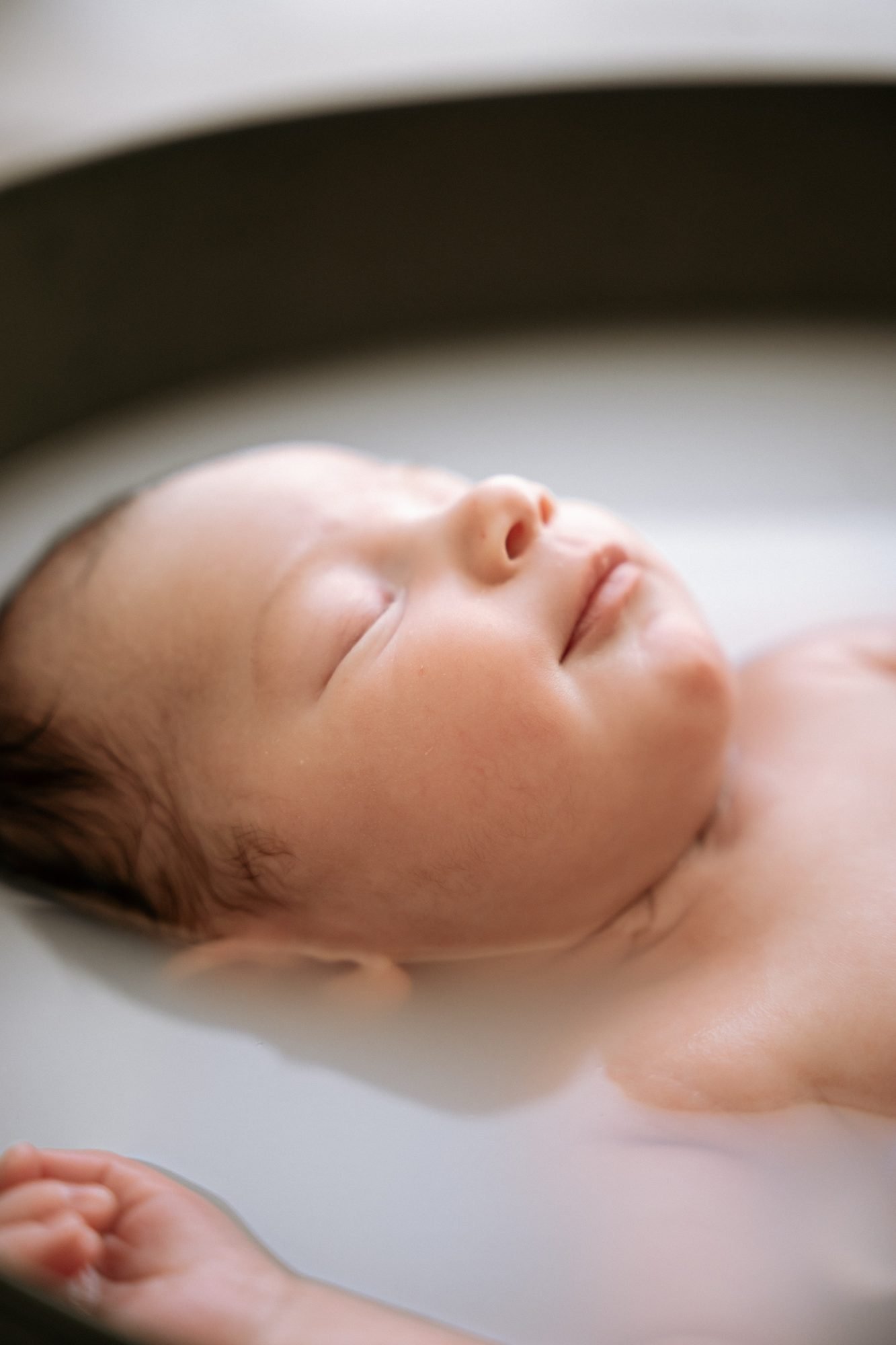 Gros plan sur le visage endormi d'un nouveau-né dans son bain