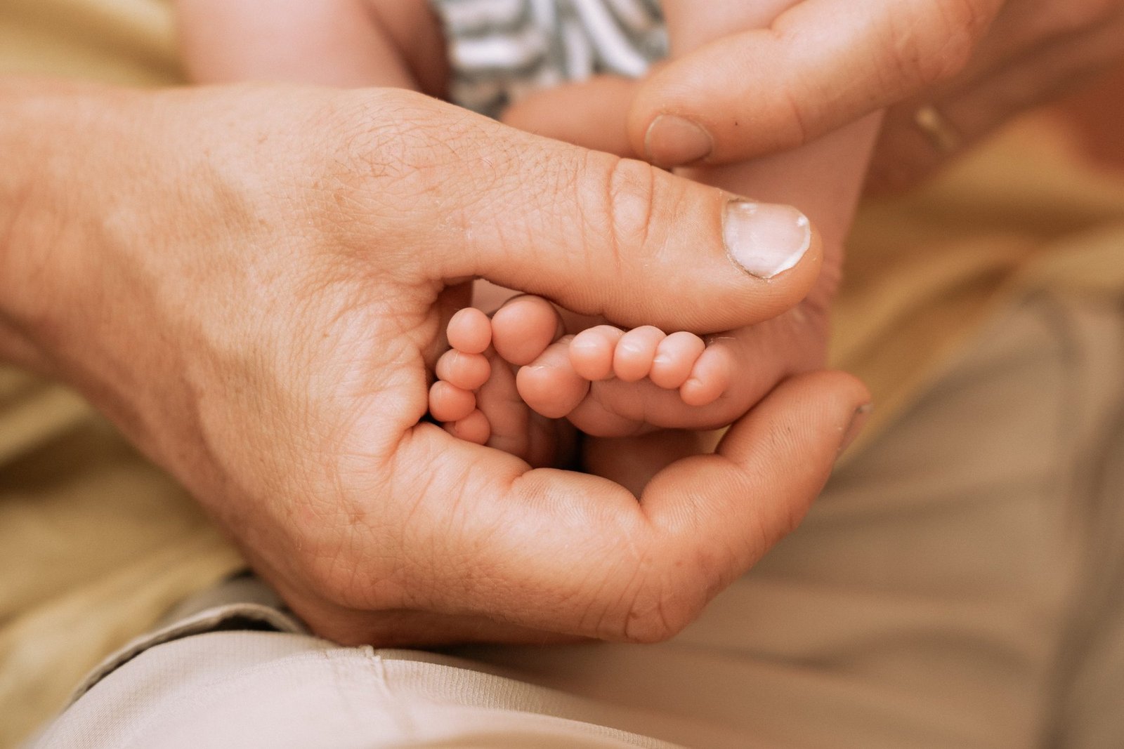 Gros plan sur les pieds d'un nouveau-né dans la main de son père