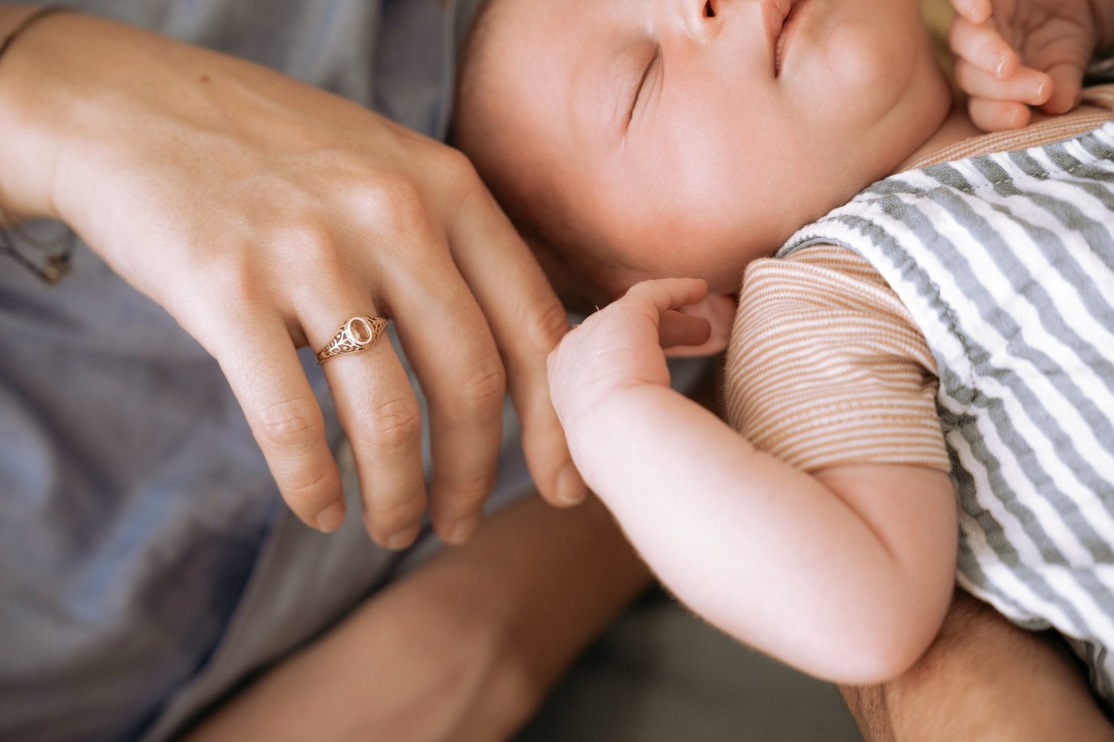 Gros plan sur la main d'une mère tenant celle de son nouveau-né, bague dorée