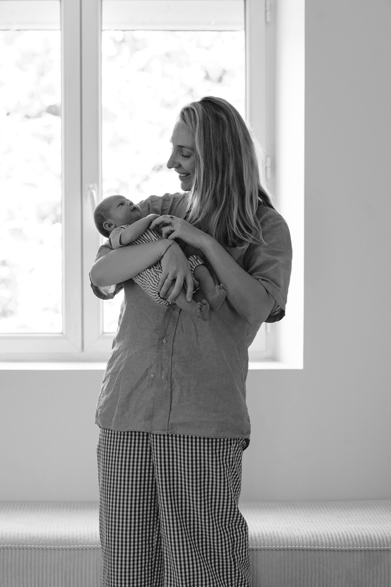 Mère tenant son nouveau-né près d'une fenêtre, noir et blanc