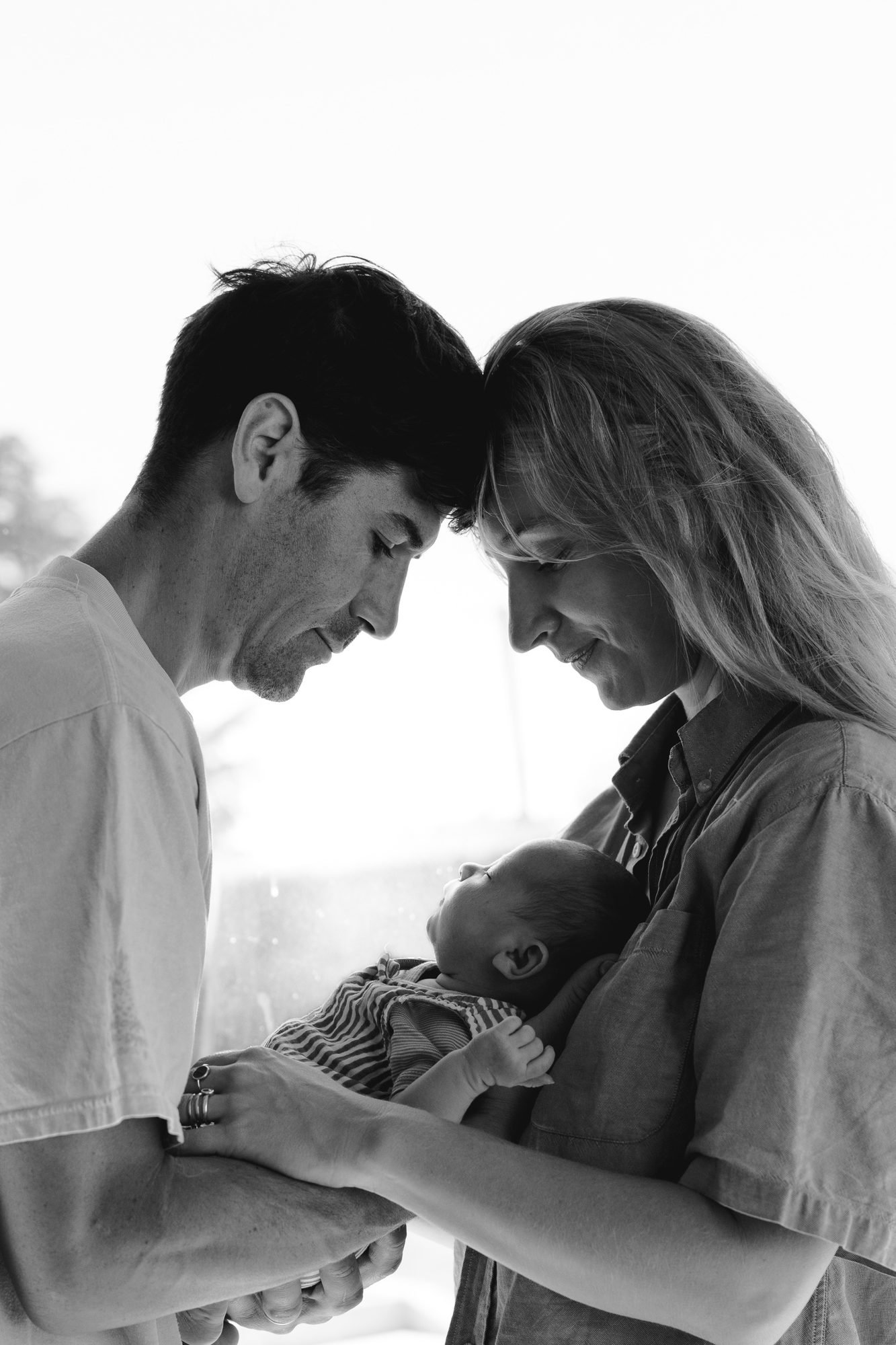 Portrait des parents front contre front avec leur nouveau-né, noir et blanc