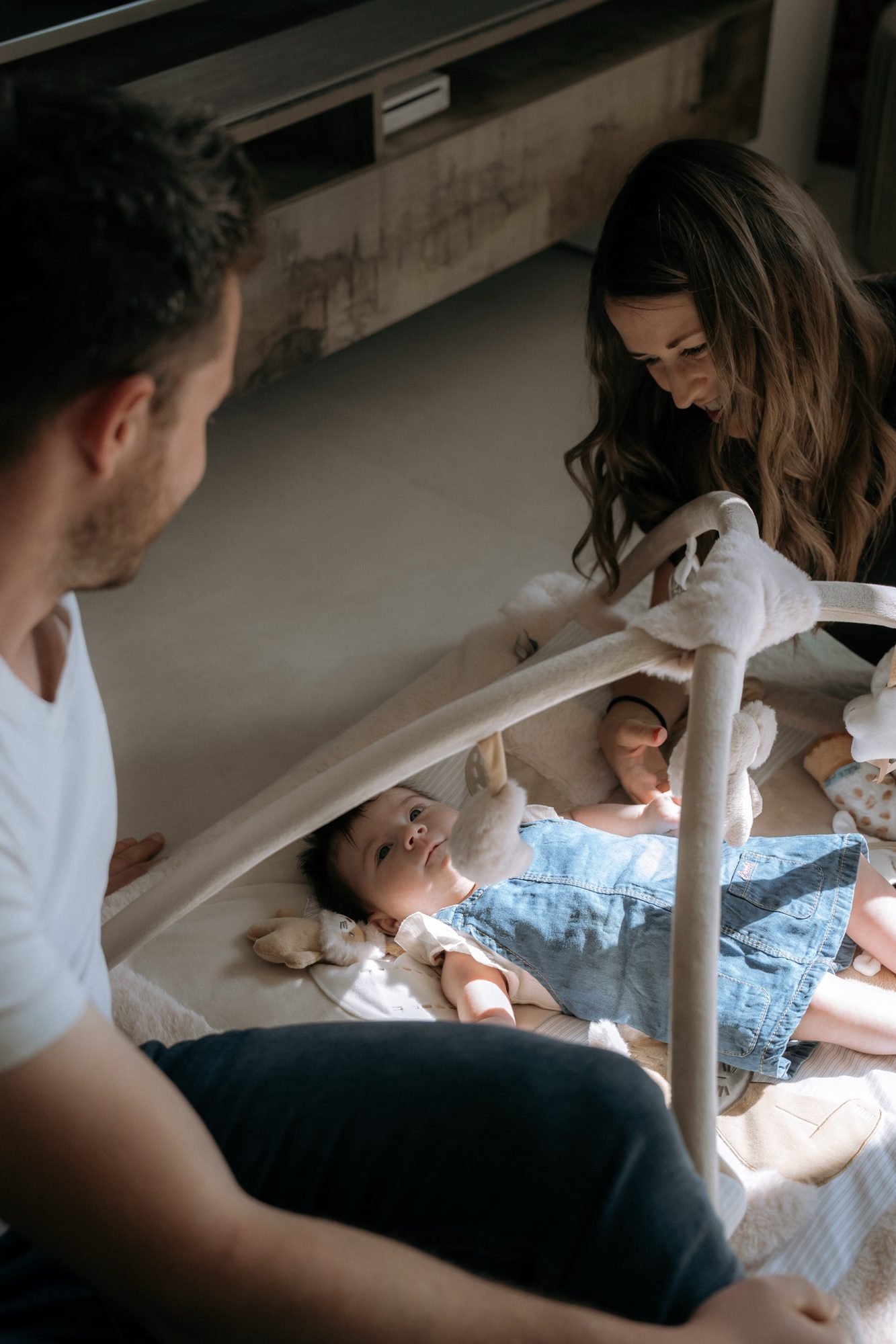 Parents jouant avec leur bébé sous un portique d'éveil