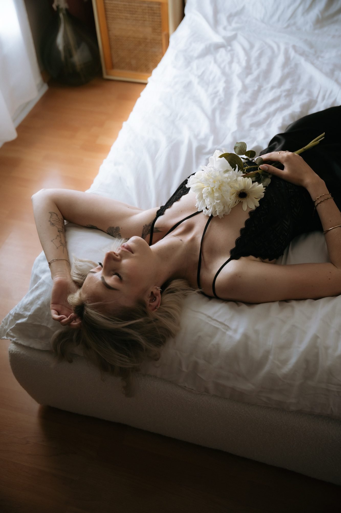 Allongée avec un bouquet blanc posé sur elle, dentelle noire