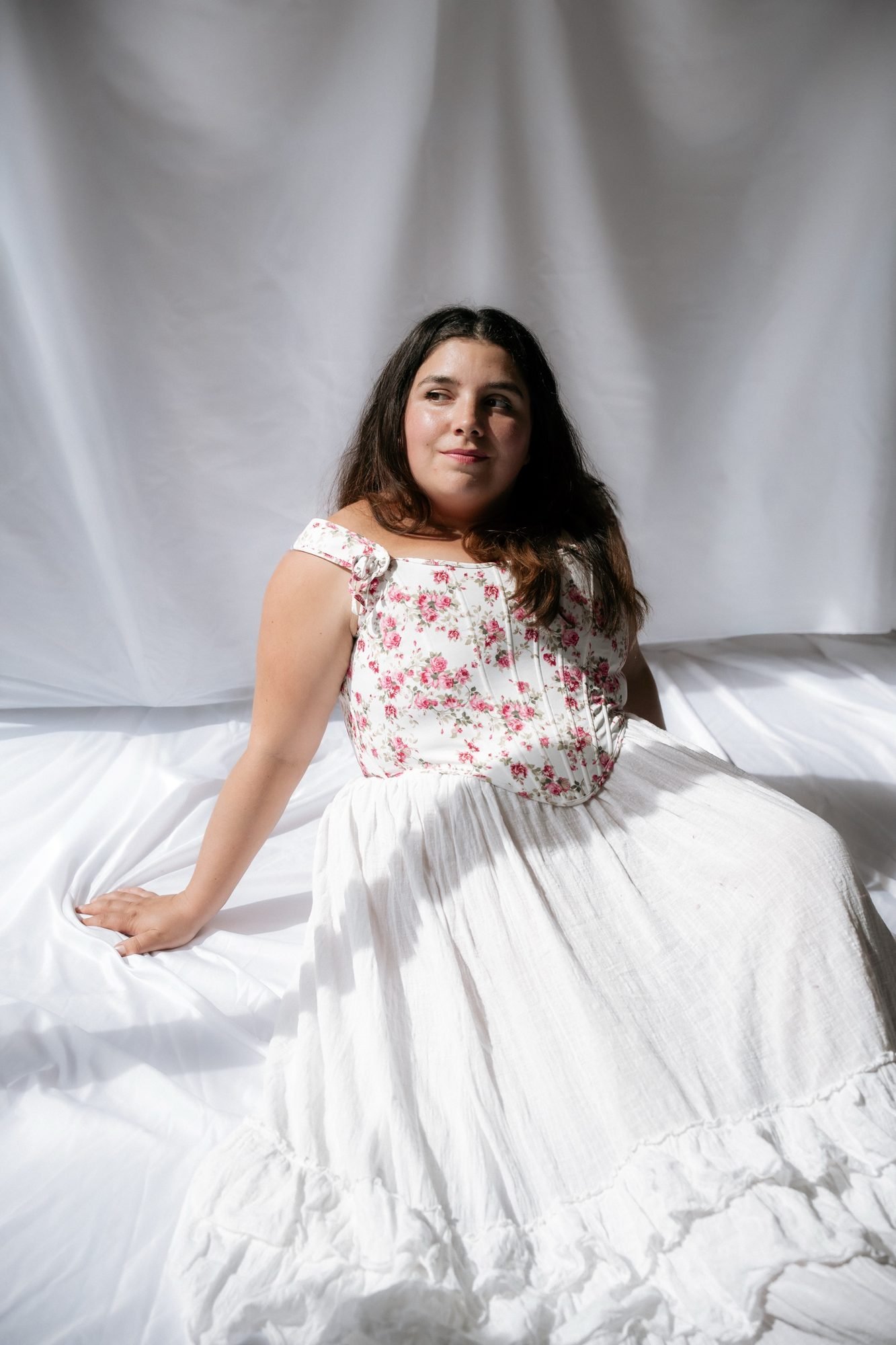 Portrait romantique, corset fleuri devant un drap blanc