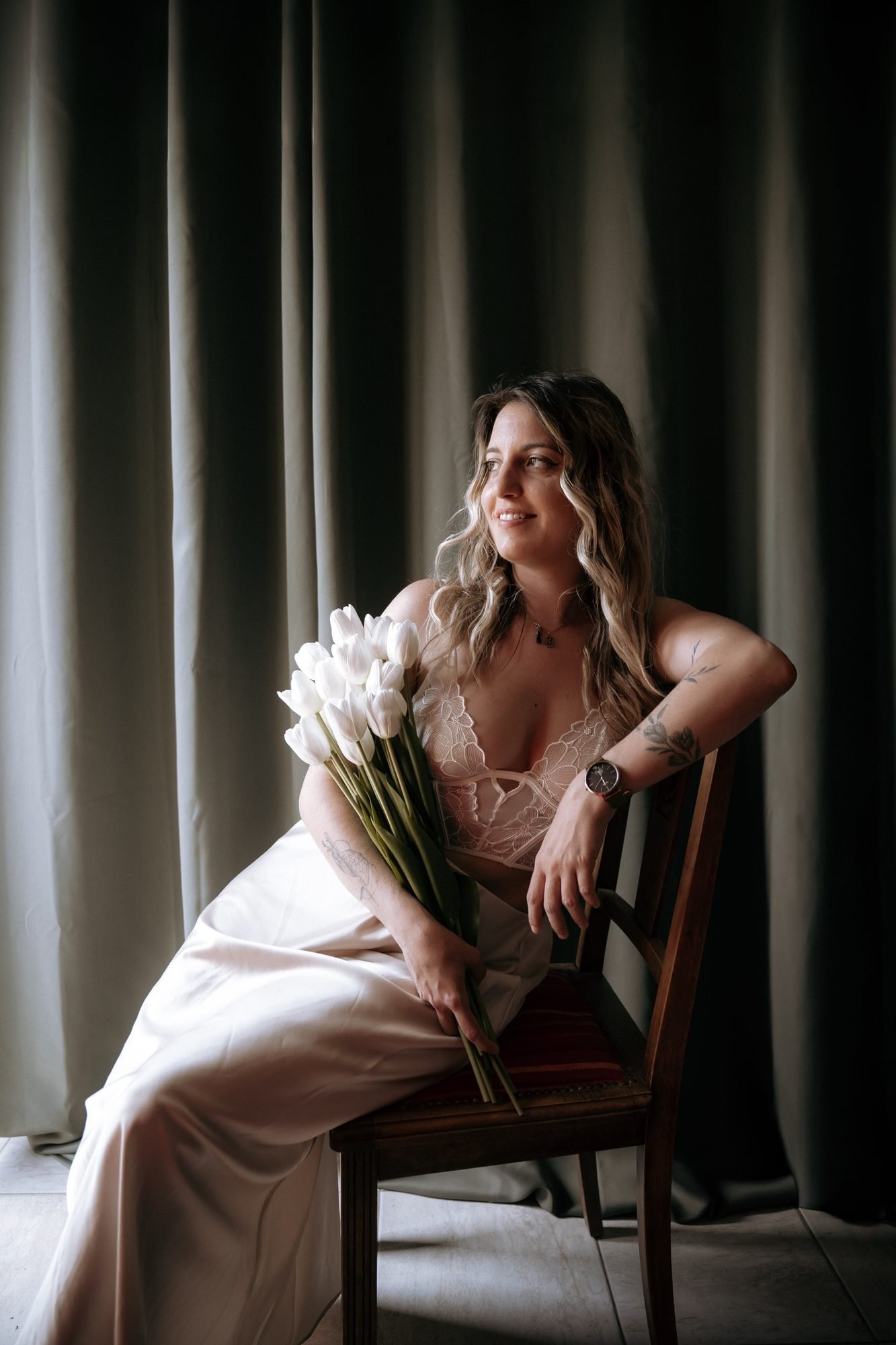 Assise avec un bouquet de tulipes blanches, regard tourné vers la lumière